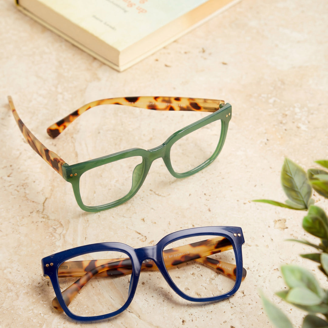 Two pairs of eyeglasses with tortoiseshell and green frames on a textured surface.