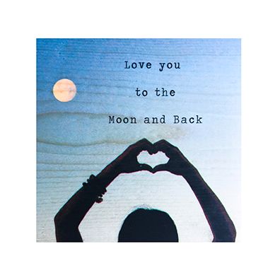 Silhouette of hands making a heart shape with text 'Love you to the Moon and Back' against a blue sky with a moon.
